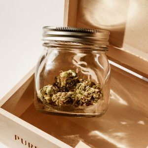 clear mason jar with cannabis inside, sitting in a wooden hinged box