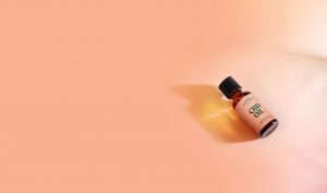 Bottle of Pure Sun CBD oil on a pink background.