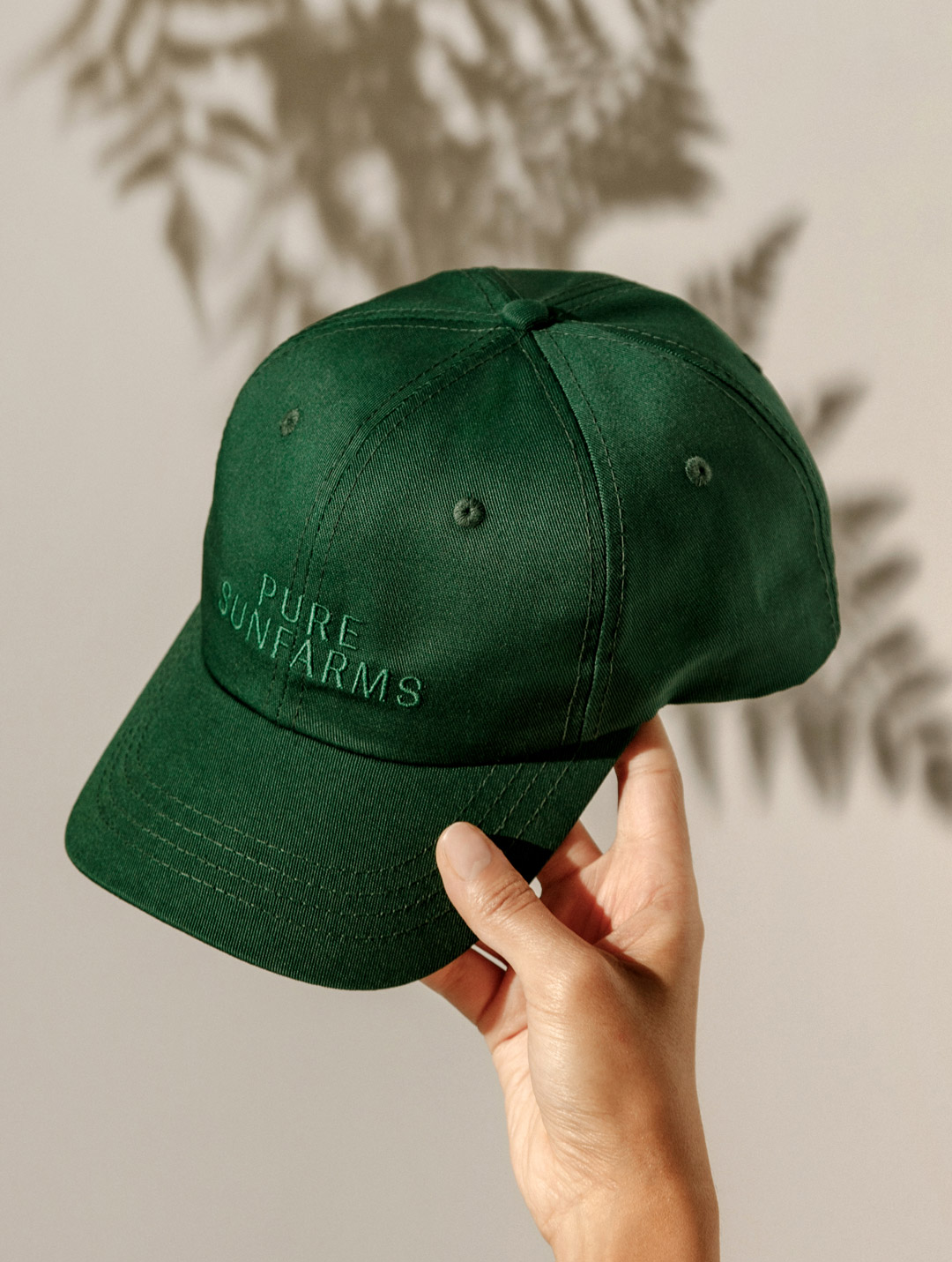 green baseball cap with embroidered "Pure Sunfarms" text.