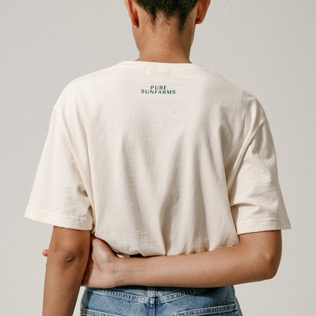 back of model wearing beige t-shirt, with label: Pure Sunfarms
