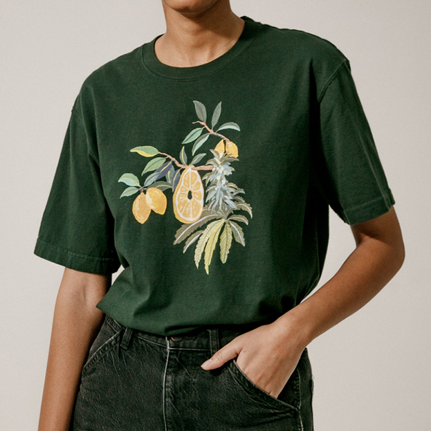 Model wearing green t-shirt with lemon and cannabis plant illustration.