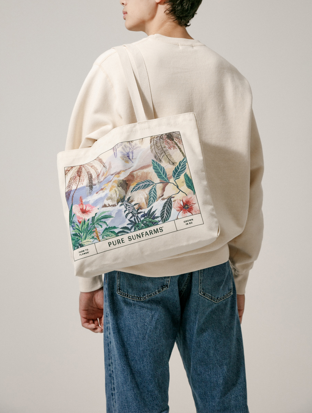 model wearing beige crewneck holding illustrated tote bag