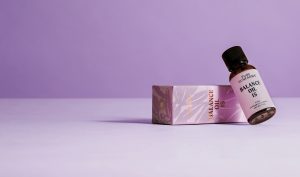 cbd oil bottle concept packaging leaning on a box on purple background