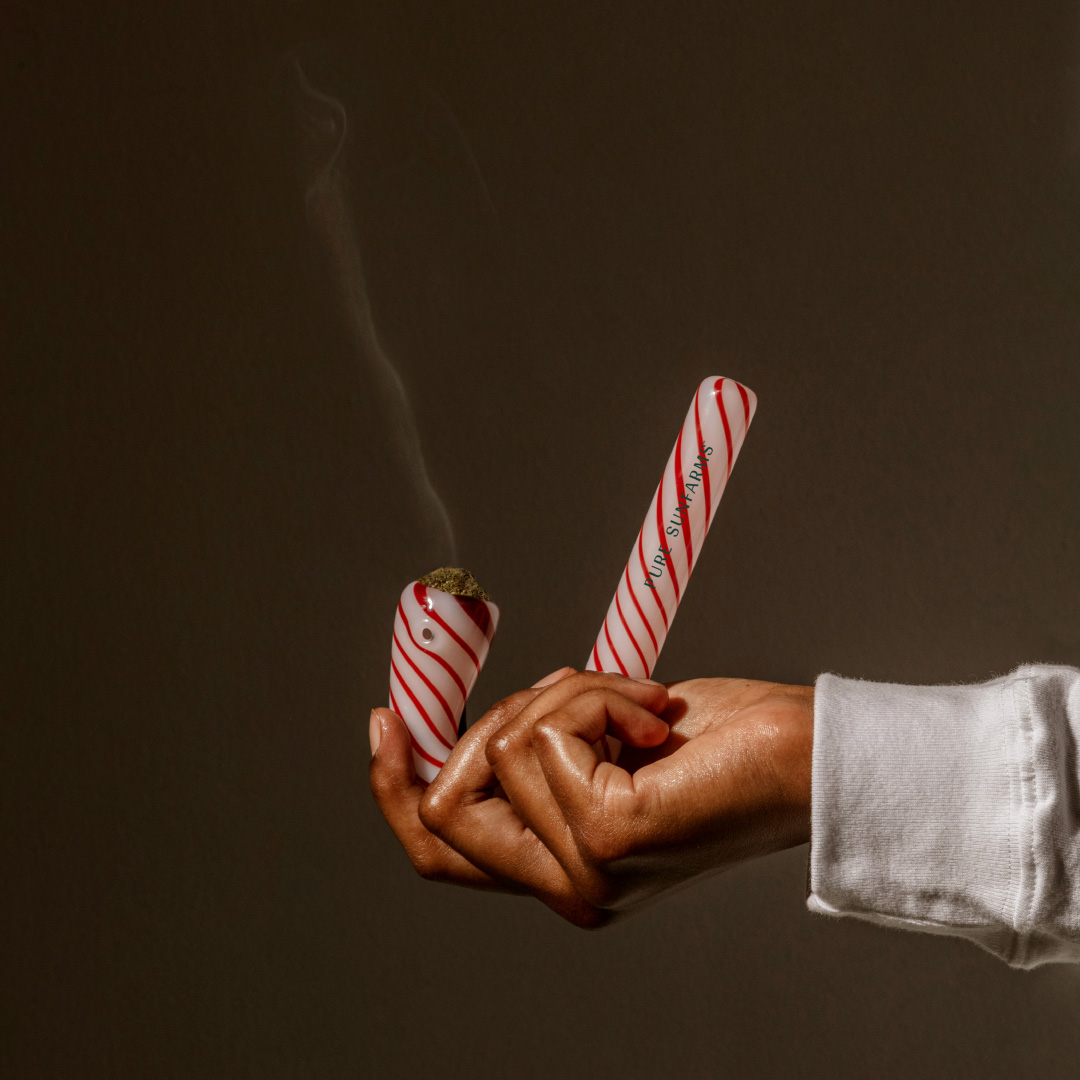 Hand holding candy cane pipe on dark background