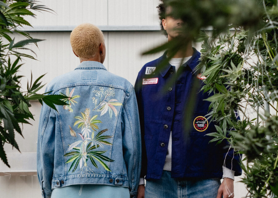 Two models wearing Pennywise 1:1 denim jacket and Jet Fuel Gelato work shirt in greenhouse with cannabis plants